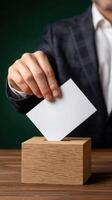 Businessman putting ballot in box on table photo
