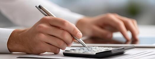 A person is using a calculator and pen to write on a paper photo