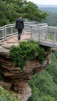 A man in a suit walks across a bridge over a cliff photo