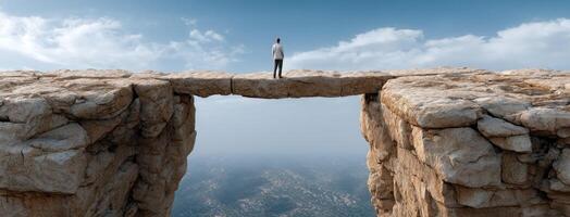 A man standing on a cliff edge looking over a gap photo