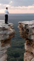 A man standing on a cliff looking out over the edge photo