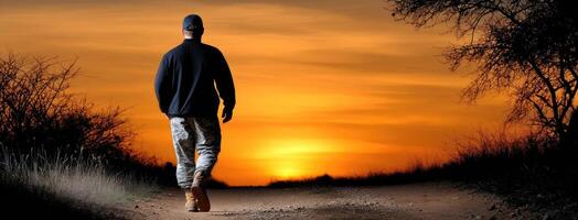 A man walking on a dirt road at sunset photo