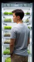 A man standing in front of a refrigerator with plants inside photo