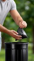 A man is putting trash in a black trash can photo