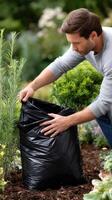 A man is picking up a black garbage bag photo