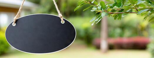 A black sign hanging from a rope in front of a house photo