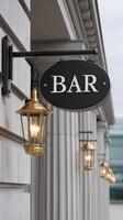A bar sign on a building with two lamps photo