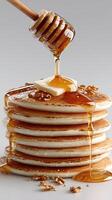 A stack of pancakes with syrup and honey being poured photo