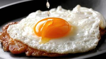 An egg is being poured onto a fried egg photo