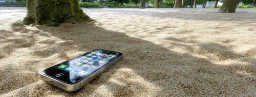 A cell phone sitting on a sandy ground photo