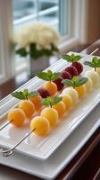 A platter of fruit on skewers with mint leaves photo