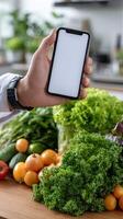 A person holding a smartphone over a table with vegetables photo