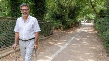 A man with crutches walking down a path photo