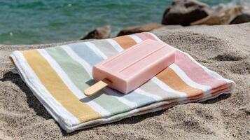 A pink popsicle on a striped towel on the beach photo