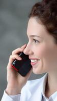 A woman in a white coat talking on a cell phone photo