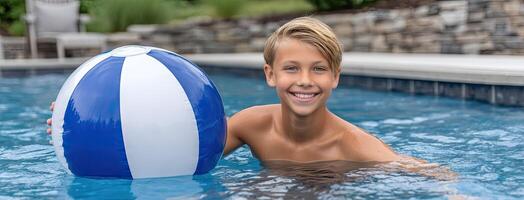 A boy is smiling while holding a blue and white beach ball photo