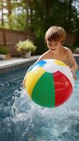 A young boy in a pool with a colorful beach ball photo