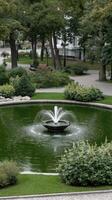 A fountain in a park with green grass and trees photo