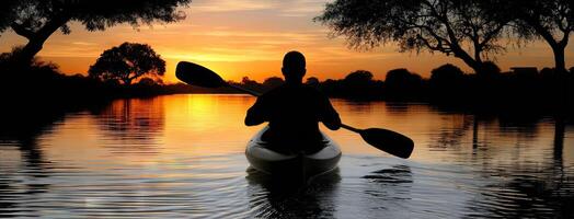 A person in a canoe paddling at sunset photo