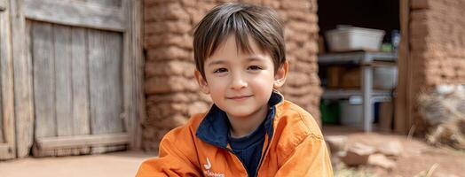 A young boy in an orange jacket sitting on the ground photo
