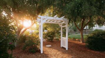 Wooden archway in a serene park at sunset, surrounded by trees and vibrant bushes photo