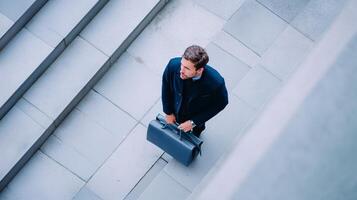 Businessman carrying briefcase walking up outdoor stairs in modern architecture setting photo