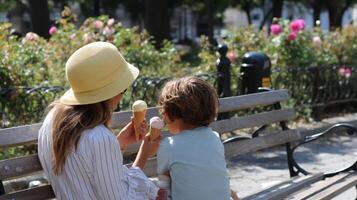 Mother and child enjoying ice cream on a sunny day in a city park surrounded by blooming flowers photo