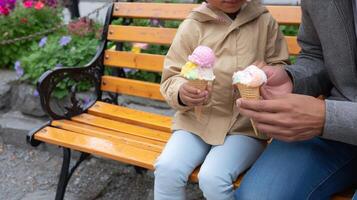 Enjoying ice cream on a park bench during a sunny afternoon in a vibrant garden setting photo