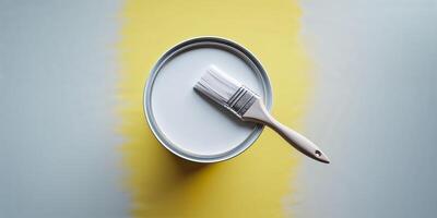 Freshly painted surface with white paint and brush resting on yellow gradient backdrop photo