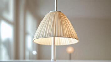 Modern hanging lamp illuminates indoor space with soft light in a stylish, minimalist setting during daytime photo