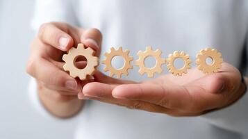 Hands holding wooden gears in various sizes, illustrating concepts of progress and teamwork in a creative workshop setting photo