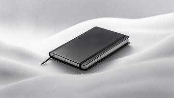 Stylish black notebook resting on soft white snow creating a serene winter atmosphere photo