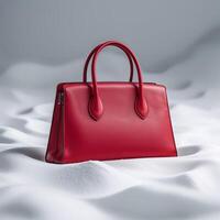 Stylish red handbag displayed on soft white fabric showcasing elegance and design photo