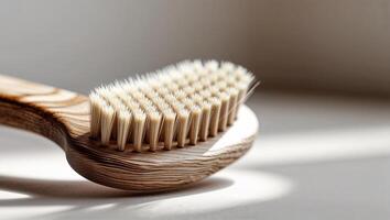 Natural bamboo toothbrush resting on a surface with soft sunlight illuminating the bristles and wooden handle in a cozy indoor setting photo