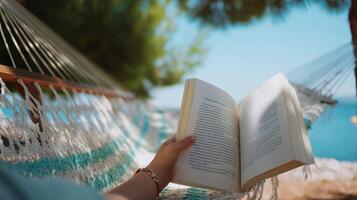 Relaxing in a hammock while reading a book by the water on a sunny day in nature photo