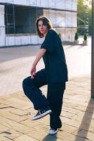 Person striking a pose in casual outfit on a sunny day at a construction site in an urban area photo