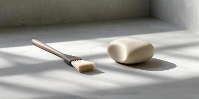 Brush and stone arranged on a concrete surface with soft shadows during daylight photo