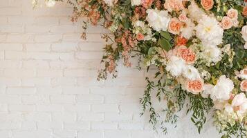Floral arrangement featuring roses and peonies against a white brick wall in a bright indoor setting photo