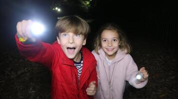 Children exploring a forest at night with flashlights, enjoying an adventure in the dark photo
