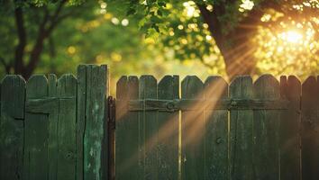 Sunlight shining through a wooden fence in a tranquil garden during early morning hours photo