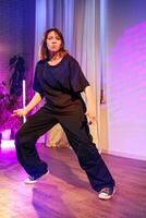Performer showcases dynamic dance moves in a vibrant indoor studio setting with colorful lighting photo