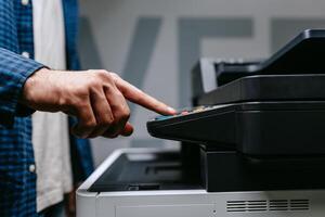 Person operating a copier in an office setting during daylight hours while preparing to make copies of documents photo