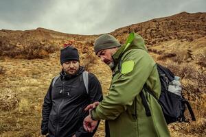 Two hikers discussing navigation on a cloudy day in a mountainous landscape during an outdoor adventure in nature photo