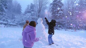 Children joyfully build a snowman in a snowy landscape during winter at a suburban park in the early evening photo