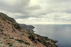 Scenic coastline view with rocky cliffs and cloudy skies at a coastal location photo