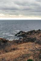 Coastal landscape with rocky shore and cloudy sky during late afternoon photo