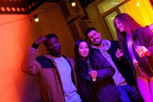 Friends enjoying a lively evening at a cozy indoor gathering with colorful lighting and drinks photo