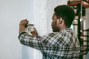 Individual configuring a security system in an industrial workspace during daylight hours photo