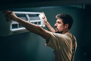 Technician installs a new air conditioning unit in a residential space during a warm afternoon photo