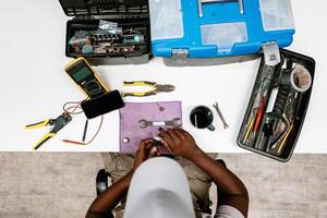 Technician repairs electronic device while surrounded by tools in workspace during daytime photo